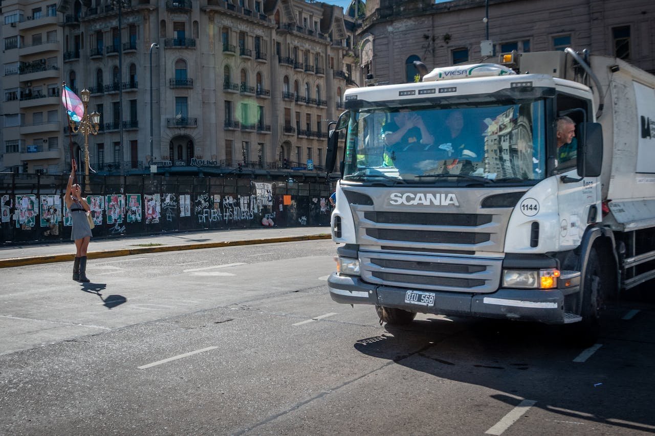 A protester with a flag confronts a truck on a sunny street in Buenos Aires, Argentina.